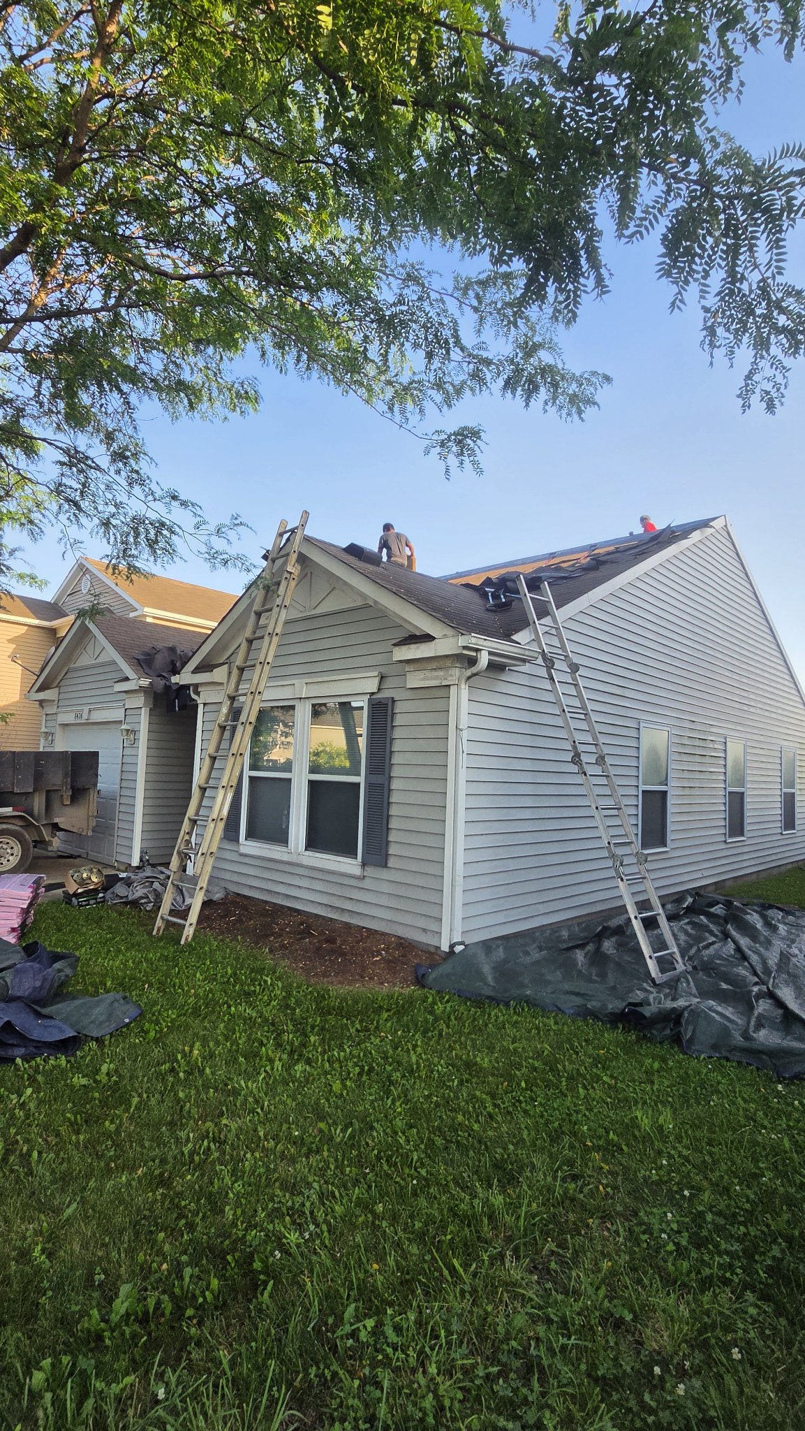 Roofing crew on ladders beginning the tear-off