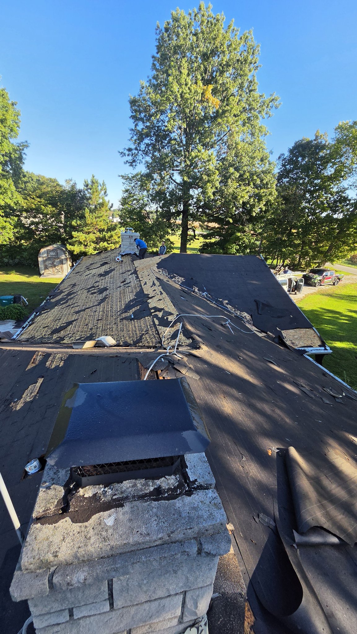 Roof replacement underway as the old roofing is removed around a chimney
